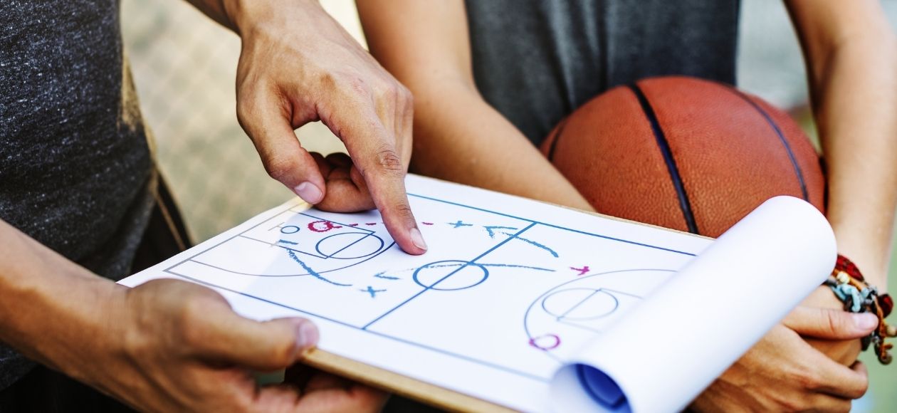 Basketball coach pointing to a clipboard showing game plan of how to beat the competition to a young player in Portland, Oregon.